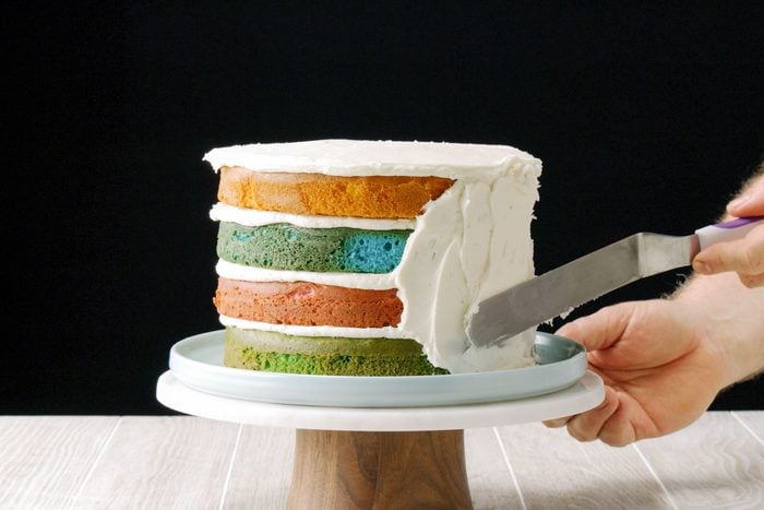 Hands Applying Frosting To Surprise Cake