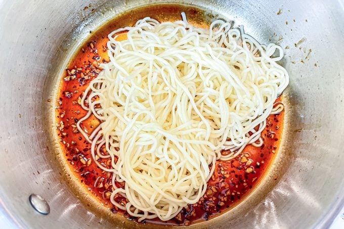 tossing noodles in sauce in a pan for Tiktok Ramen