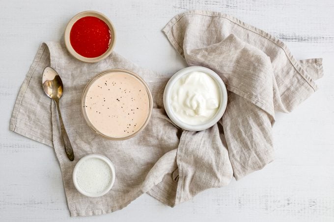 Dish of dipping sauce surrounded by sriracha, sour cream, and buttermilk