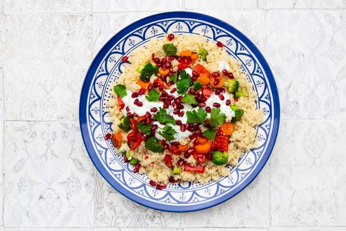 Couscous with grilled vegetables: carrots, peppers and broccoli and yoghurt-mint sauce, parsley, pomegranate seeds