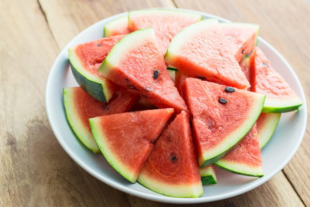 Slices of watermelon on white plate on a wooden background