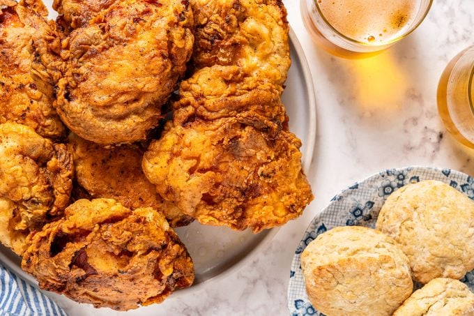 Crispiest Fried Chicken Thighs in Plate on Marble Surface with some Drinks