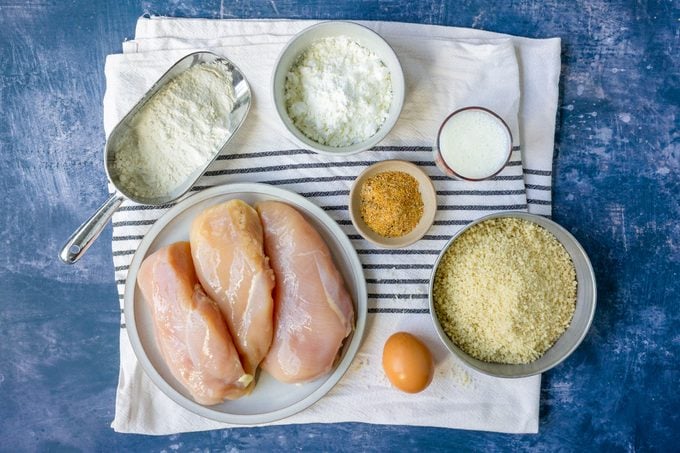 Ingredients for Oven Fried Chicken Breast on a cloth on blue surface