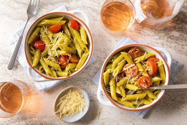 Penne With Pesto served in bowl with fork and juice