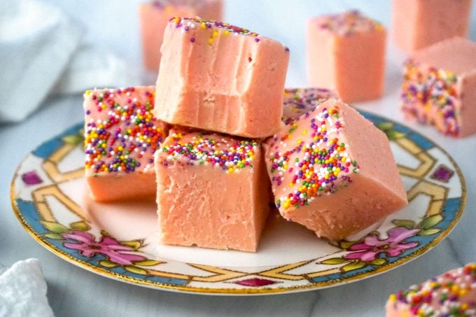 Pink Lemonade Fudge with Sprinkles on a plate with a bite take from one piece
