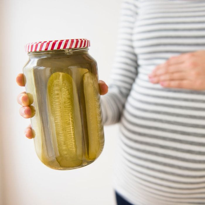 Pregnant woman holding jar of pickles
