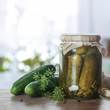 Jar With Pickled Cucumbers On Wooden Table In Kitchen