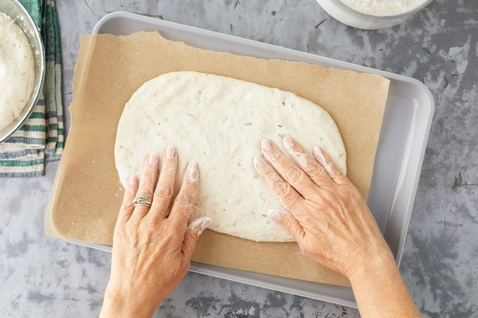 Spreading Fougasse Dough with hands to make a Oval Shape