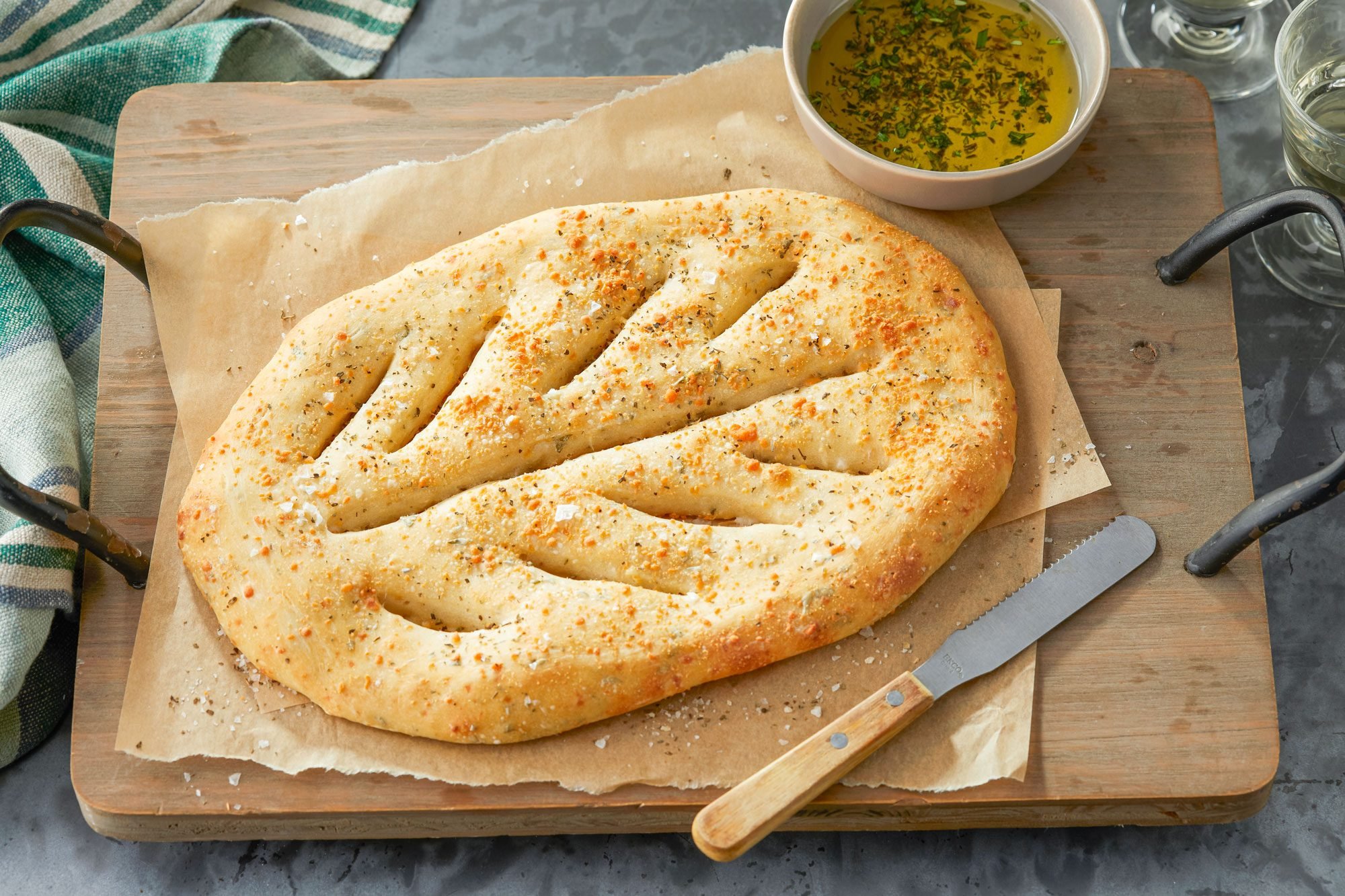 Fougasse on a Baking Paper on Wooden Serving Plate with Knife
