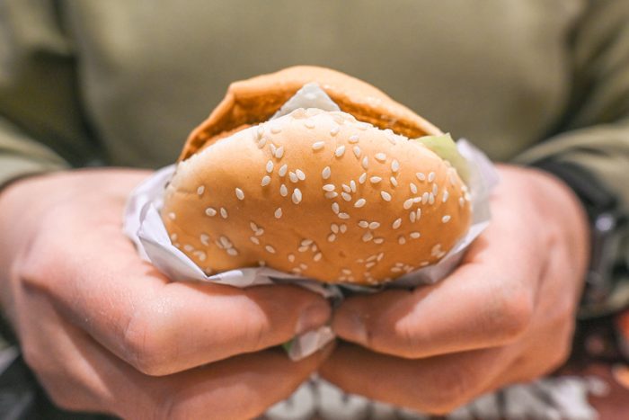 Person enjoys a hamburger inside a burger king fast food restaurant