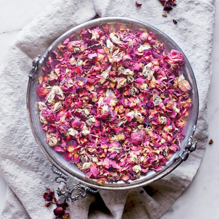 dried rose petals in a bowl on a white towel