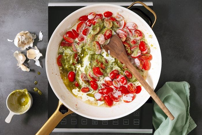 Pesto Sauce with cream, cherry tomatoes, garlic and olive oil in pan