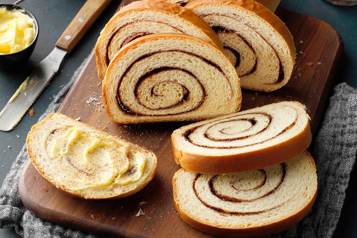 Cinnamon swirl bread loaf with slices shingled off, overhead.