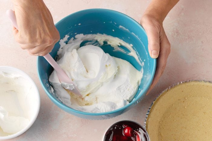 making cheesecake in a teal mixing bowl