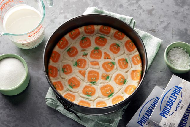Tiktok No Bake Halloween Cheesecake cookie crust in a cake pan surrounded by other ingredients