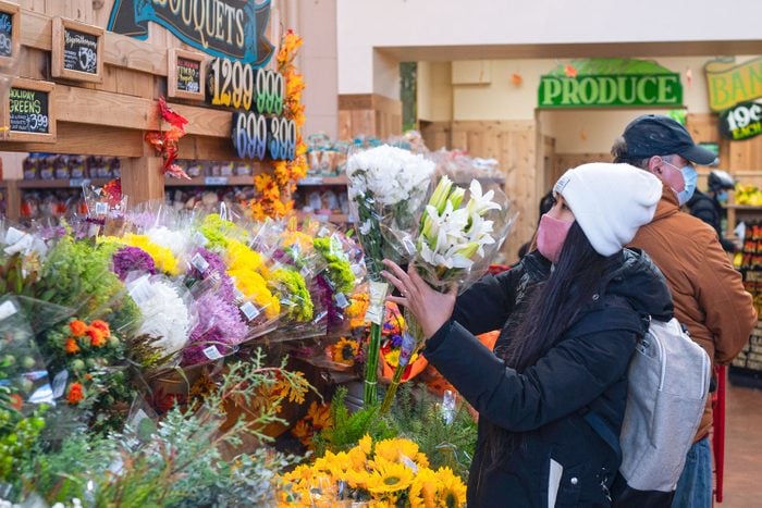 A Woman Shopping At Trader Joe's In New York City selects a fresh bouquet of flowers from the floral department of the grocery store