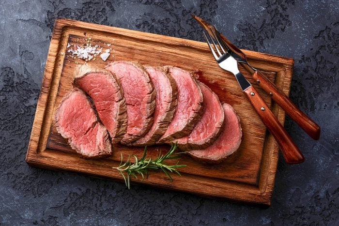 Sliced Grilled Tenderloin Steak Roastbeef On Wooden Cutting Board On Dark Background