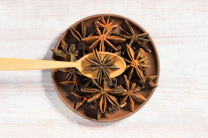 Anise (Anisum vulgare) on a brown clay plate on a wooden background with spoon