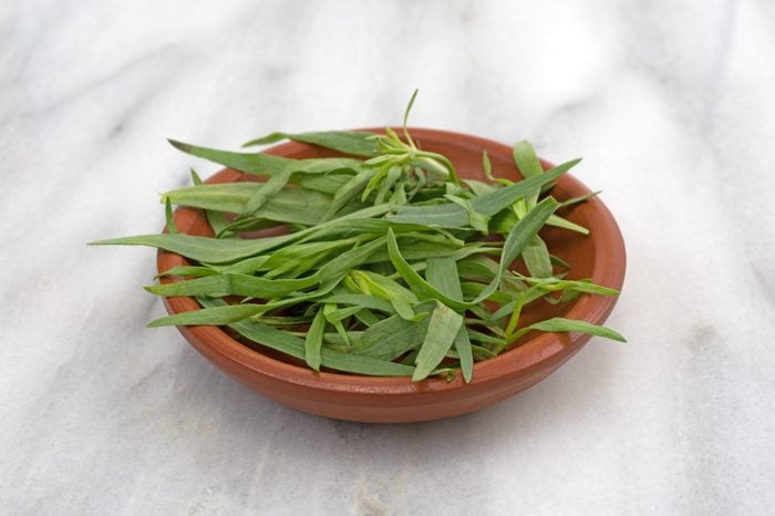 Bowl of tarragon leaves on a table
