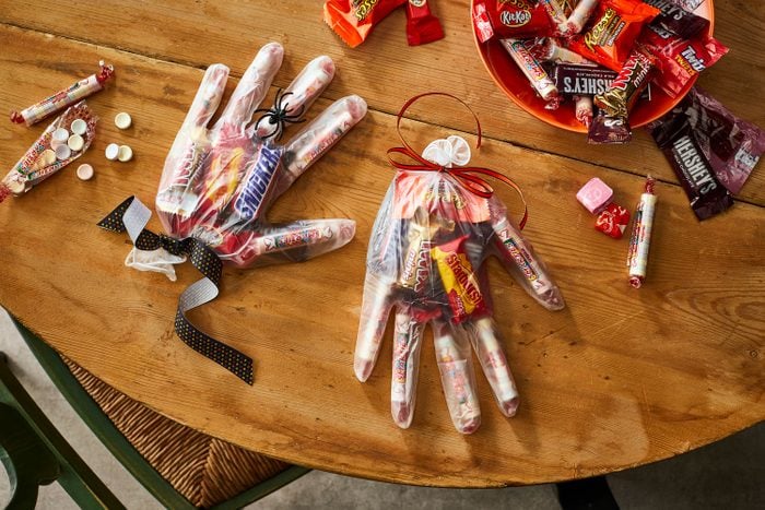 Halloween Candy Treat Bag in a Vinyl Glove, filled with candy and sweet treats, laying on a wooden table in a residential kitchen