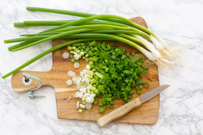 Chopped and whole spring onions on wooden board