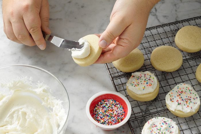 Decorating cookies with frosting and colourful sprinkles
