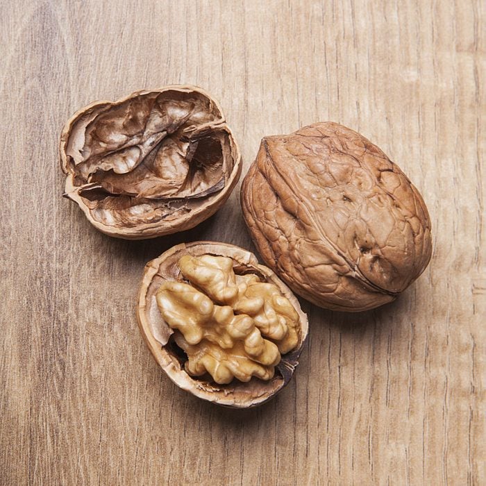Whole unpeeled and broken walnuts on wooden background.