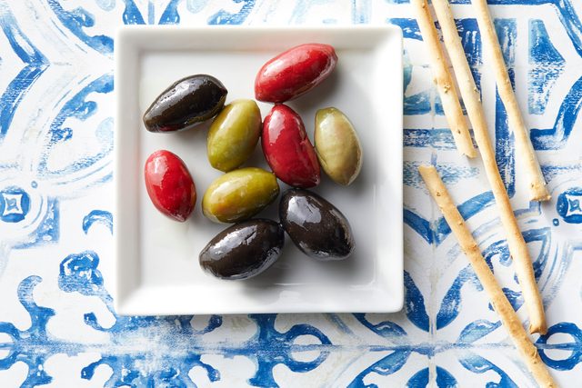 Cerignola olives on a square dish on blue and white background