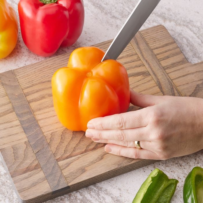 Cutting Bell pepper on wooden chopping board