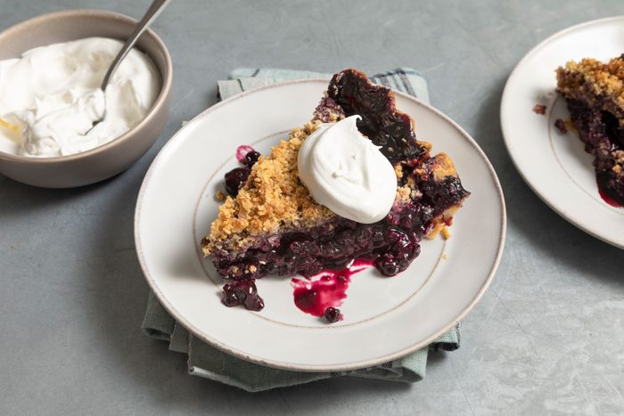 Blueberry Crumble Pie with wipcream on top served in a plate