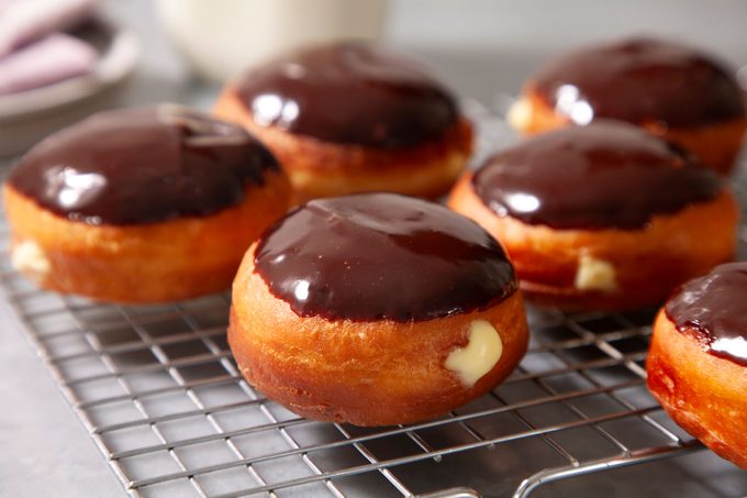Chocolate dipped doughnuts resting on wire racks