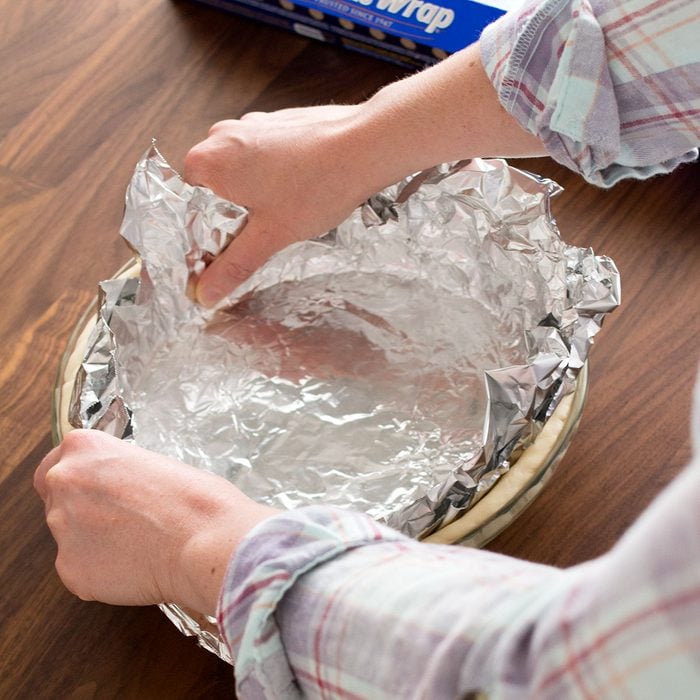 Putting foil over dough in pan