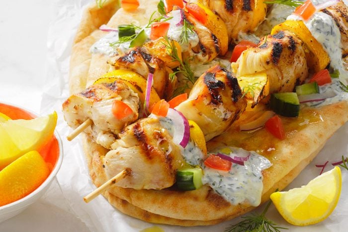 Chicken Souvlaki Pitas served with bread and lemon on a white table