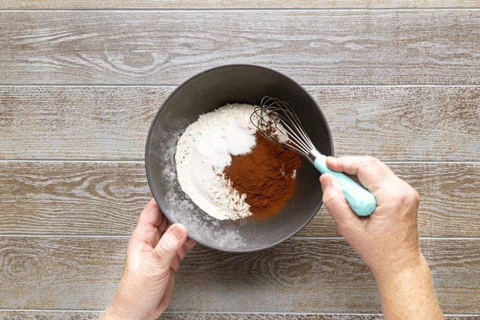 Combining the flour, cocoa in a small bowl using a spatula on a wooden surface