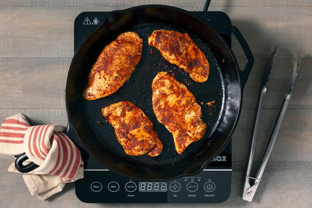 Chicken pieces being sauted in a large skillet