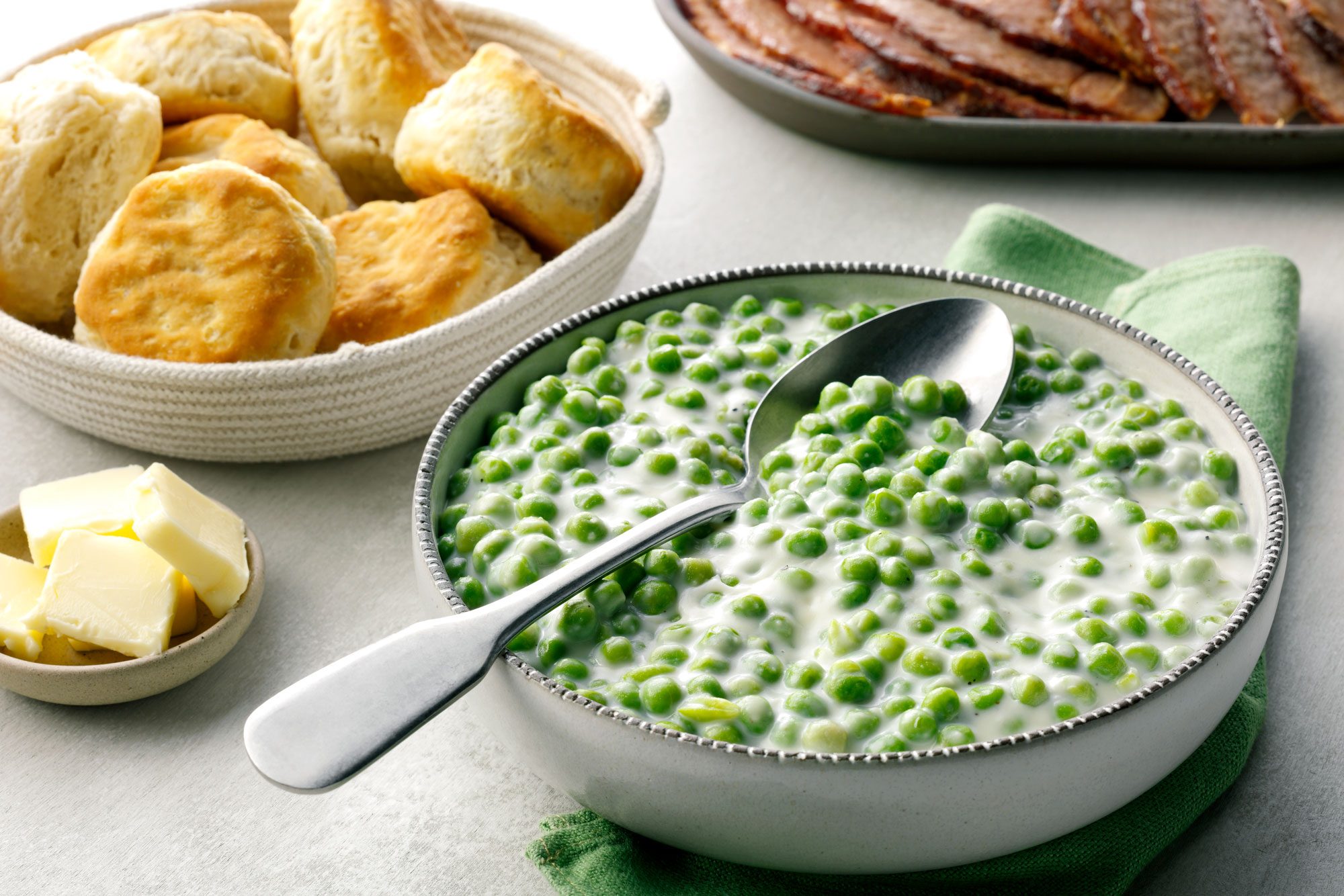 Creamed Peas served in a bowl with buns and butter