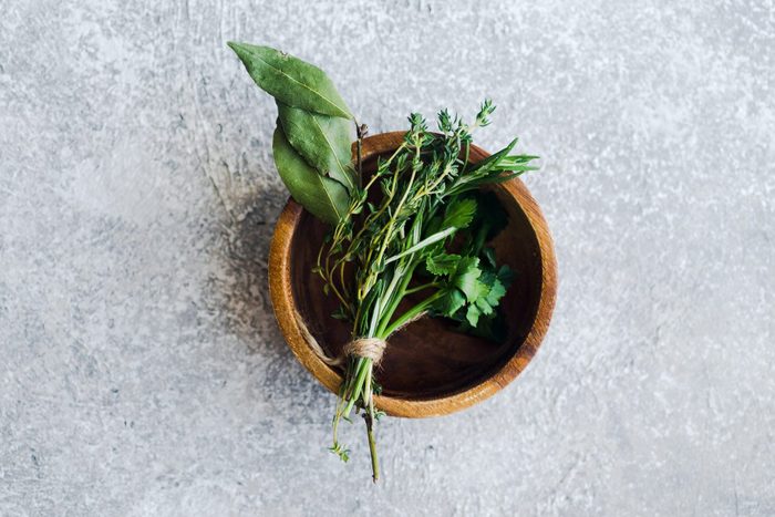 Bouquet garni with bay leaves and fresh herbs de provence on gray textured background