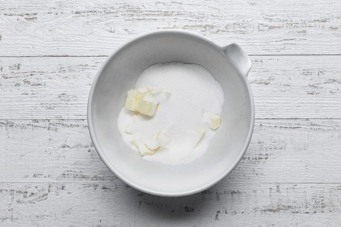 A white bowl with butter and sugar on a table