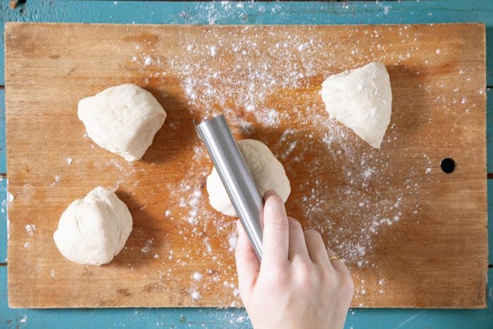 A person kneading dough on a cutting board.