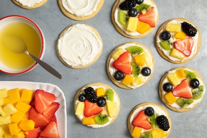 cream cheese on cookies with topping of fruits on them