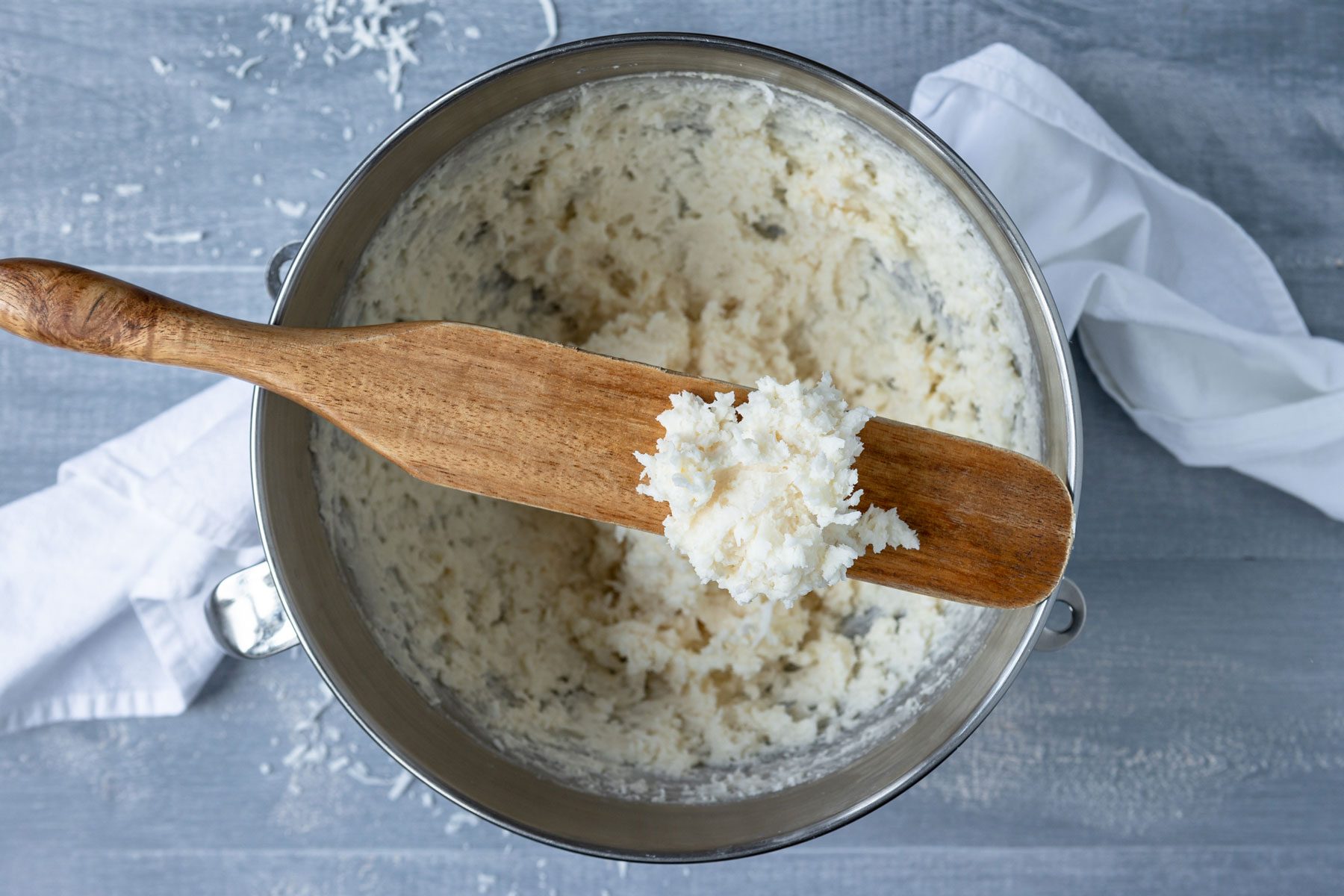 adding shredded coconut in a mixture of cheese