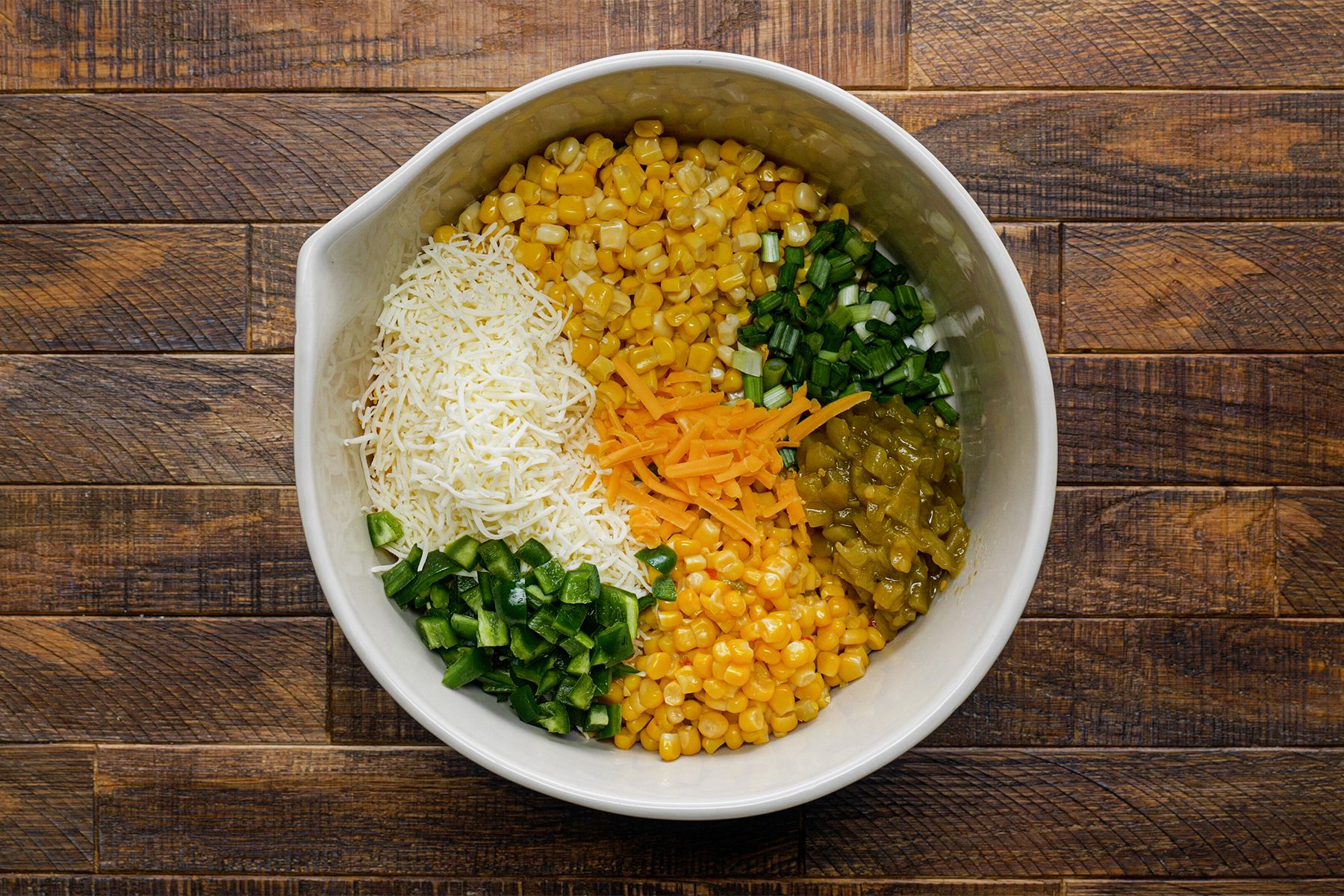 Bowl With canned corn, diced green onions, green chilies and diced jalapeno in it