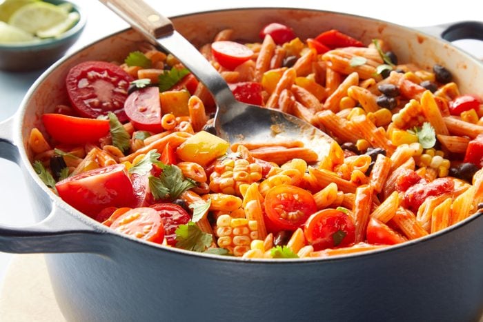 One Pot Enchilada Pasta served in a large pot with tomatoes and limes 