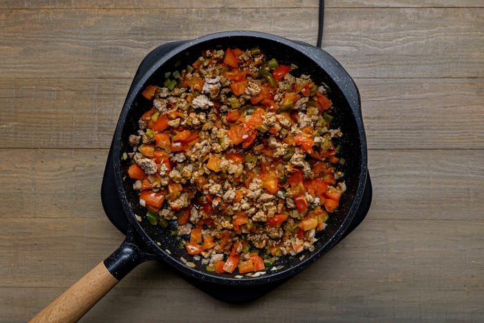 Tomatoes and chiles mixed in the sausage mixture in a large skillet
