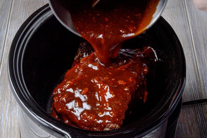 Return the brisket to the cooker and add barbecue sauce