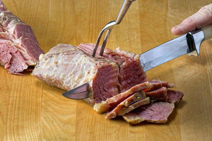 Cutting the beef into small pieces with a knife on a wooden surface