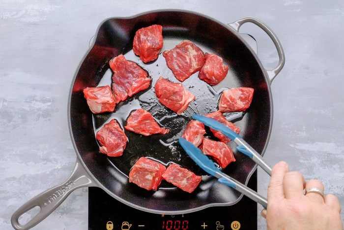 Raw beef cooking in skillet