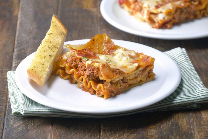Lasagna served on plate with garlic bread
