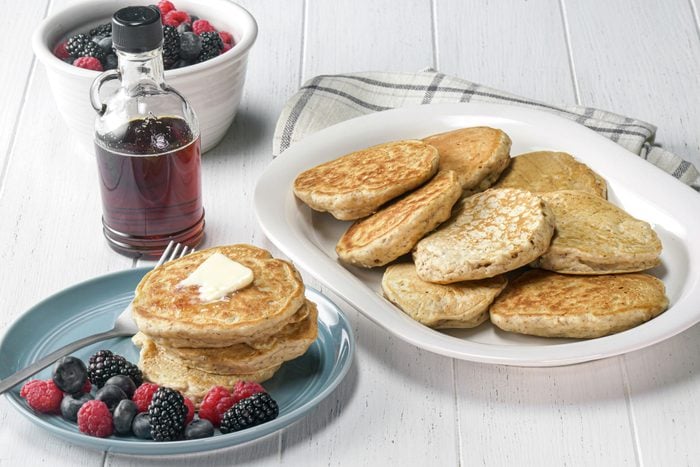 Vegan pancakes served with butter, maple syrup and mixed berries on the side