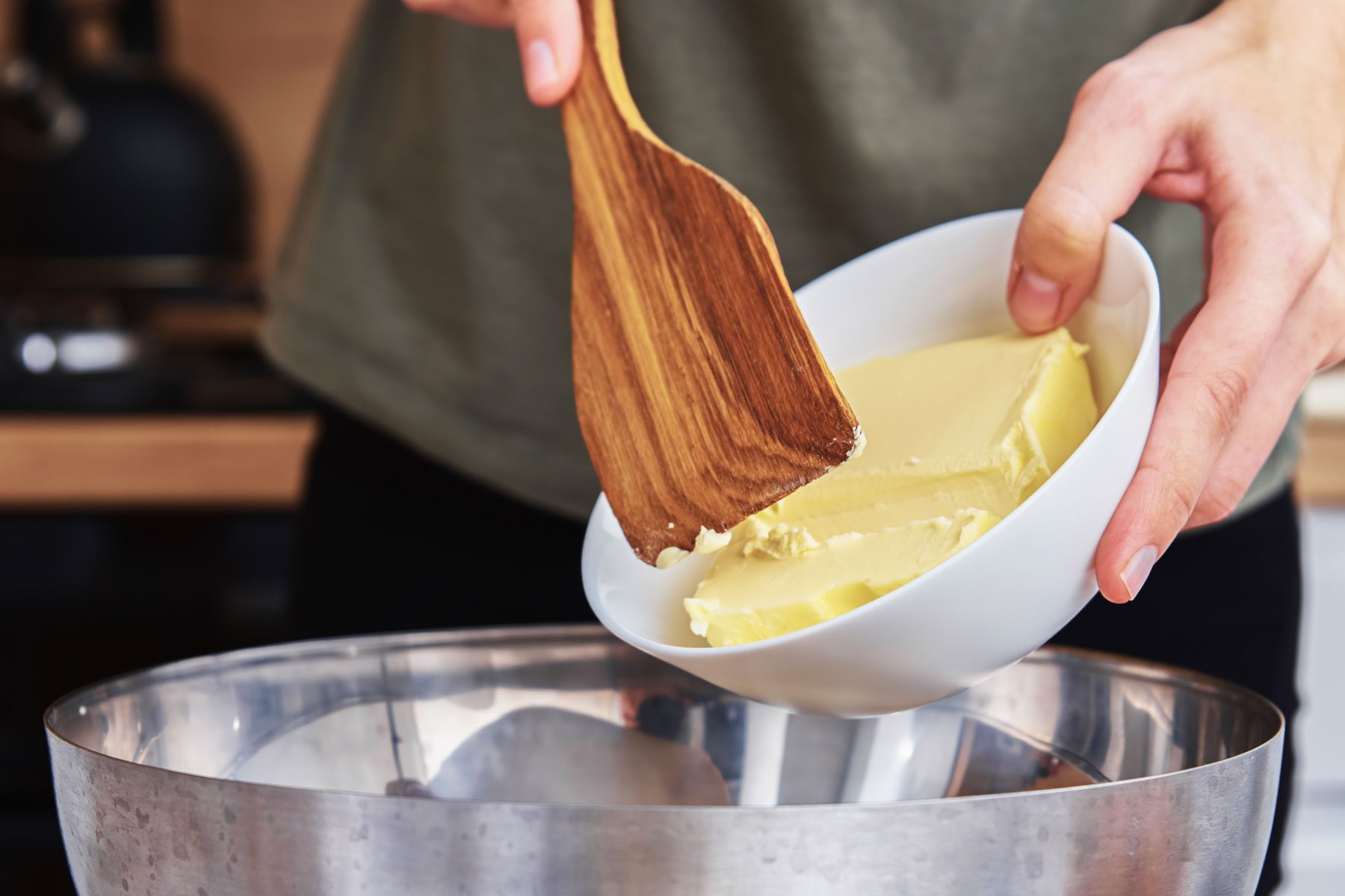 A person putting butter in a large bowl for cooking
